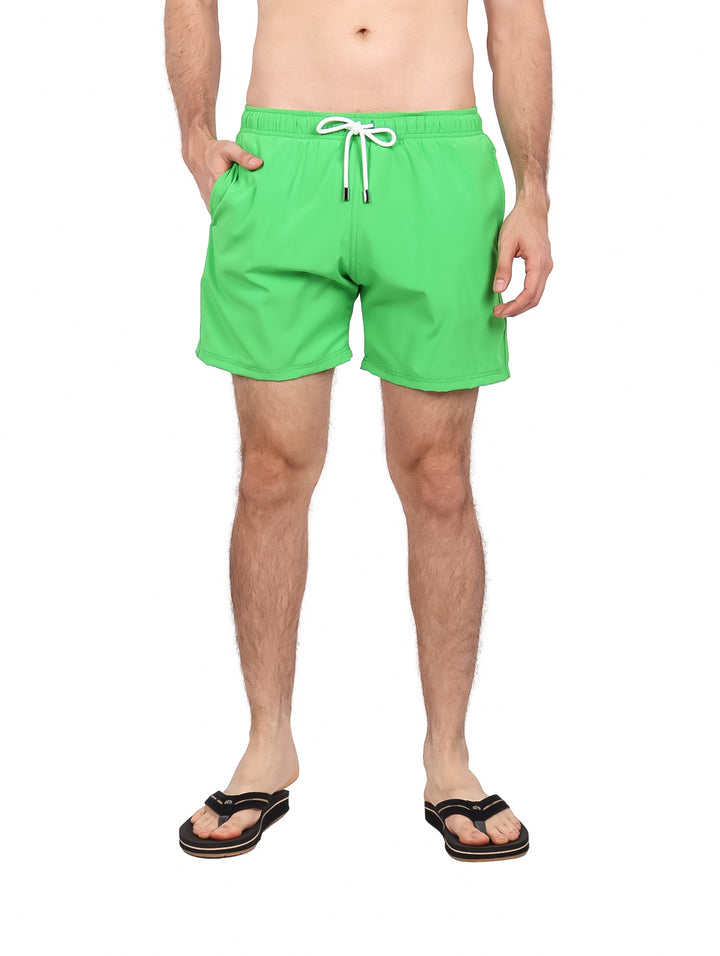 Hombre vistiendo un traje de baño corto color verde brillante con cordones blancos en la cintura.