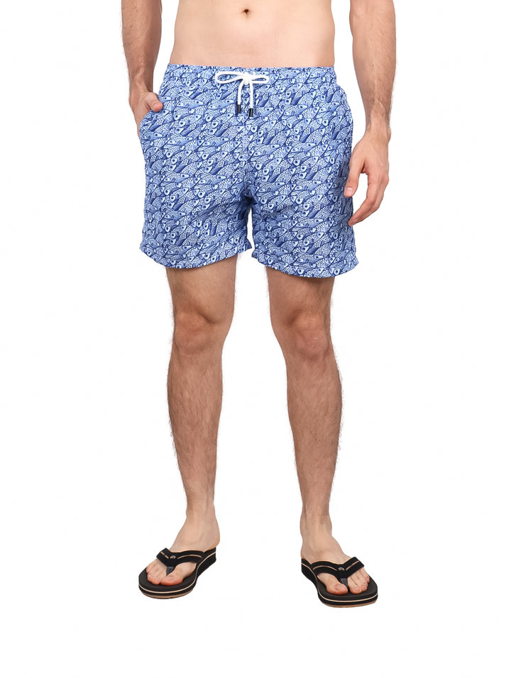 Hombre vistiendo un traje de baño corto color azul con estampado blanco y cordón ajustable.