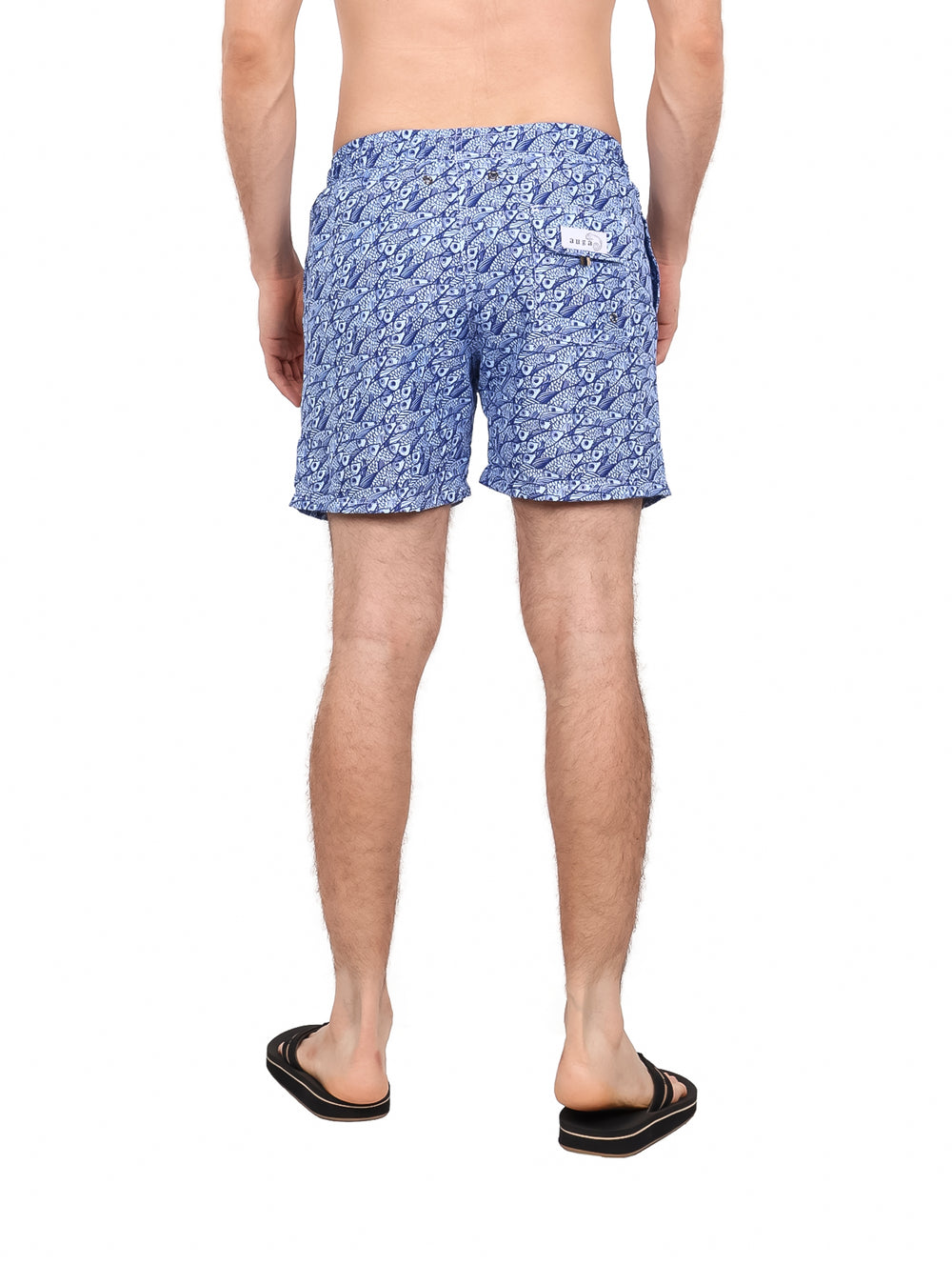 Hombre vistiendo un traje de baño corto color azul con estampado blanco y cordón ajustable.