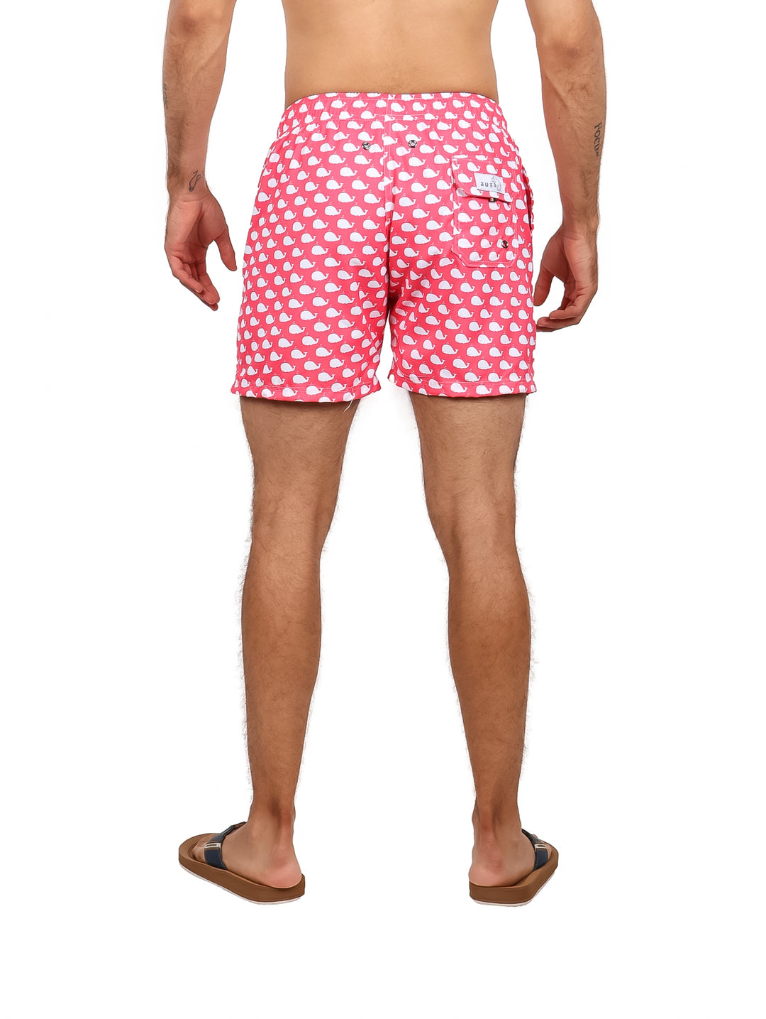 Hombre vistiendo un traje de baño corto color rosa con estampado de ballenas blancas.