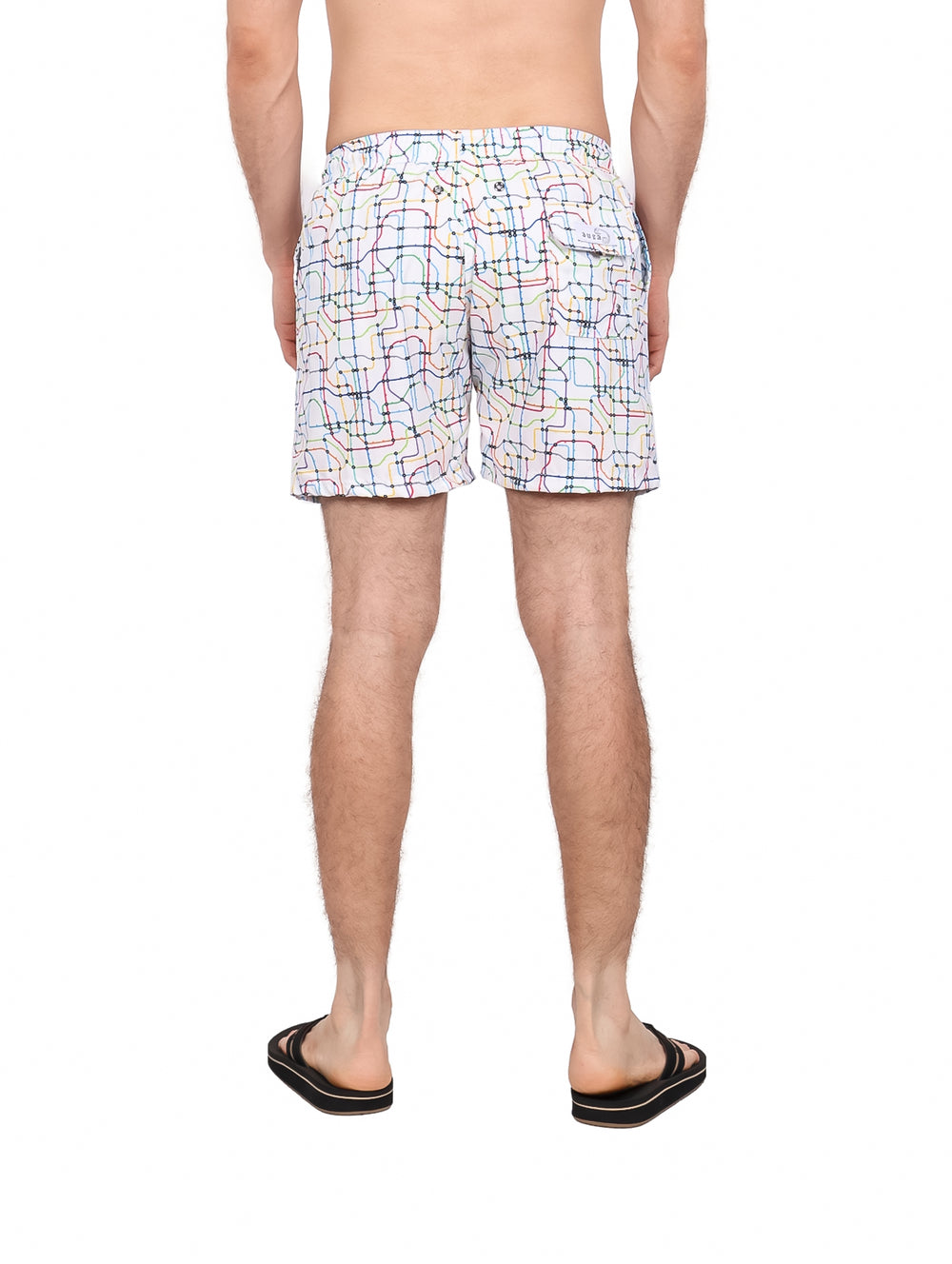 Hombre vistiendo un traje de baño corto color blanco con estampado de líneas multicolores.