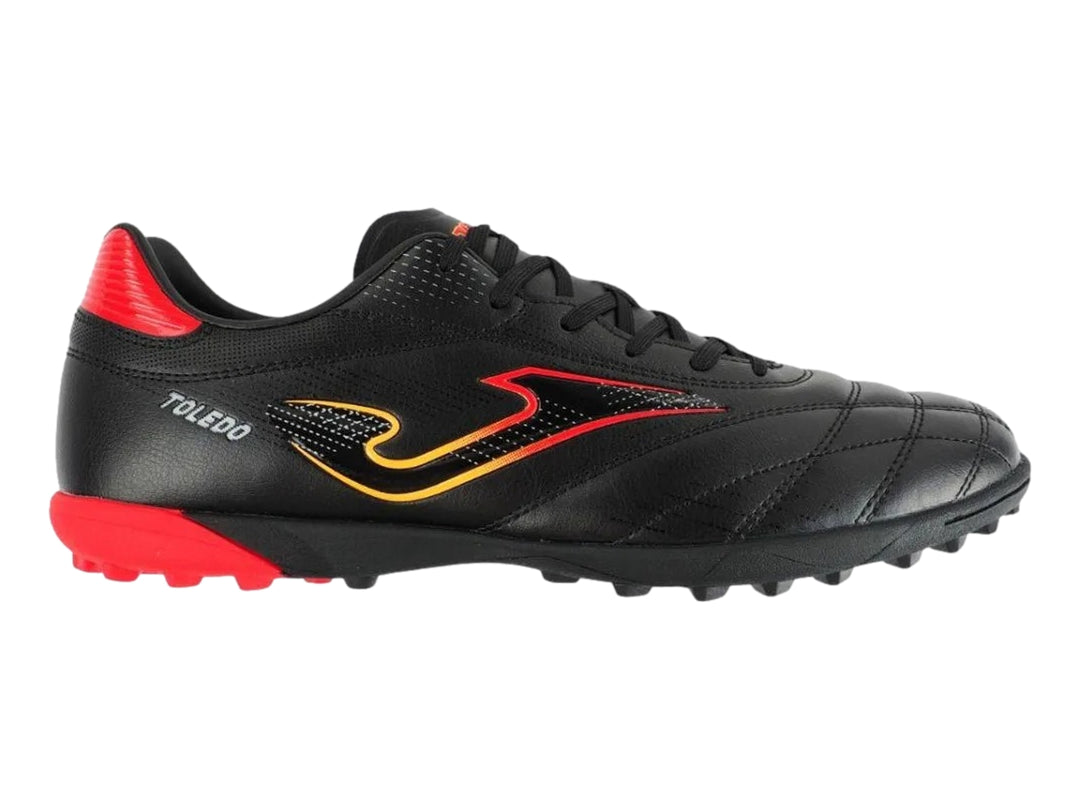 Zapato de fútbol Joma Toledo color negro con detalles en rojo y amarillo, diseño para superficie artificial.