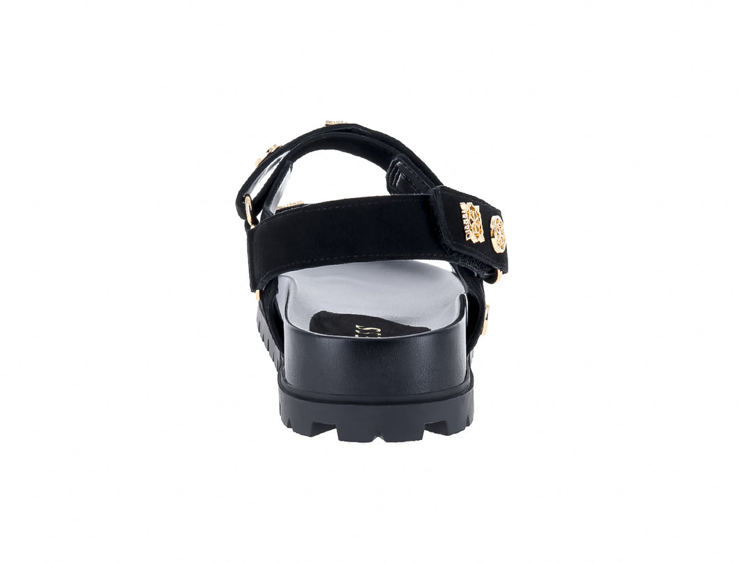 Sandalia negra de plataforma con correas y detalles metálicos dorados de la marca GUESS.