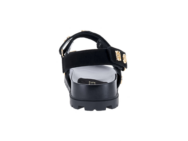 Sandalia negra de plataforma con correas y detalles metálicos dorados de la marca GUESS.