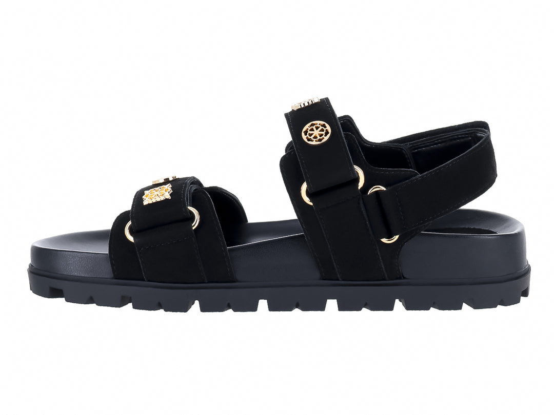 Sandalia negra de plataforma con correas y detalles metálicos dorados de la marca GUESS.