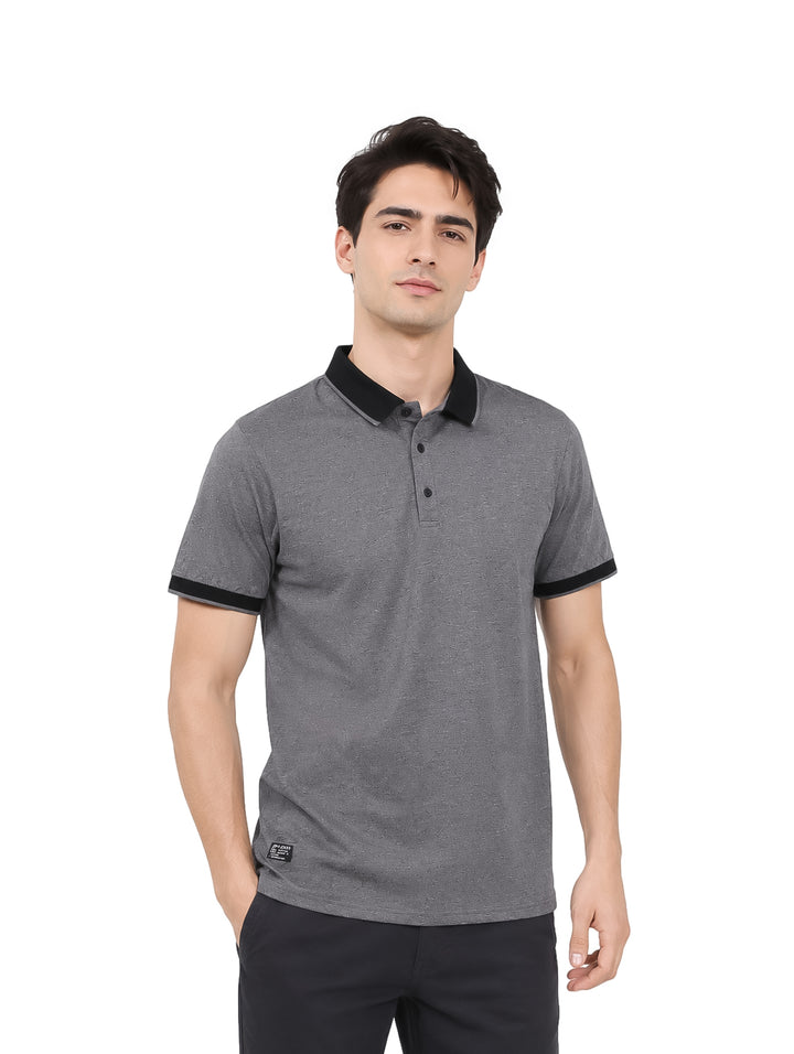Hombre vistiendo playera polo color gris oxford con detalles en negro en el cuello y mangas.