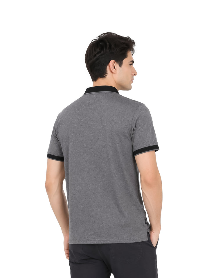 Hombre vistiendo playera polo color gris oxford con detalles en negro en el cuello y mangas.