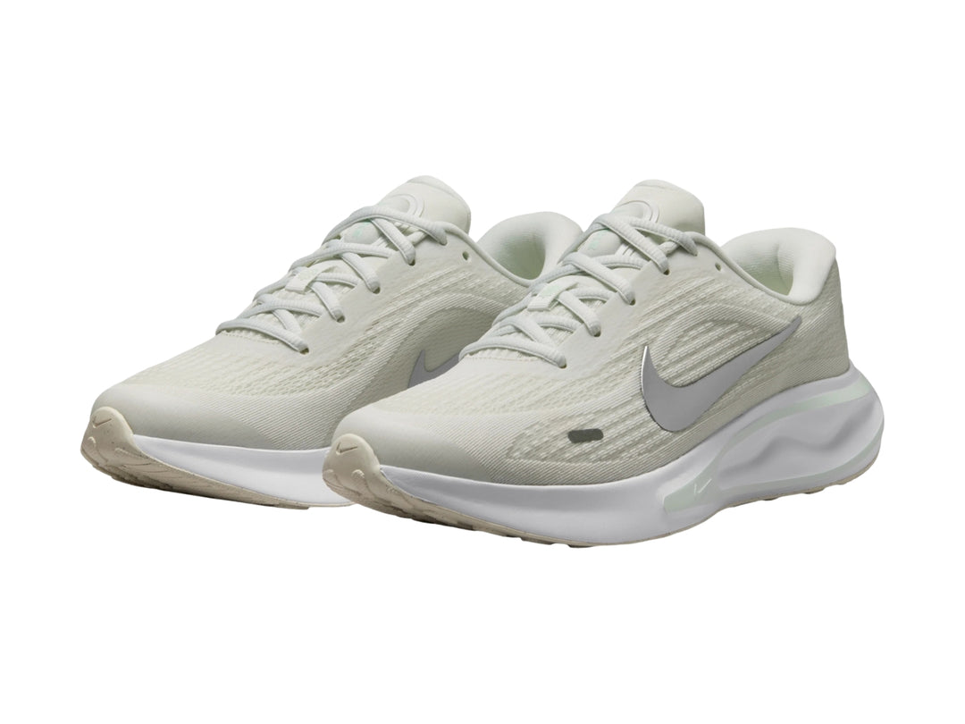 Tenis deportivos Nike Journey Run color blanco con detalles en verde claro y logotipo plateado.