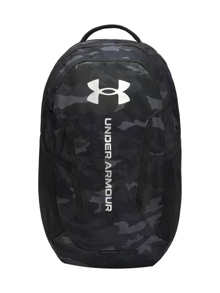 Mochila Under Armour negra con estampado de camuflaje y logotipo blanco frontal.