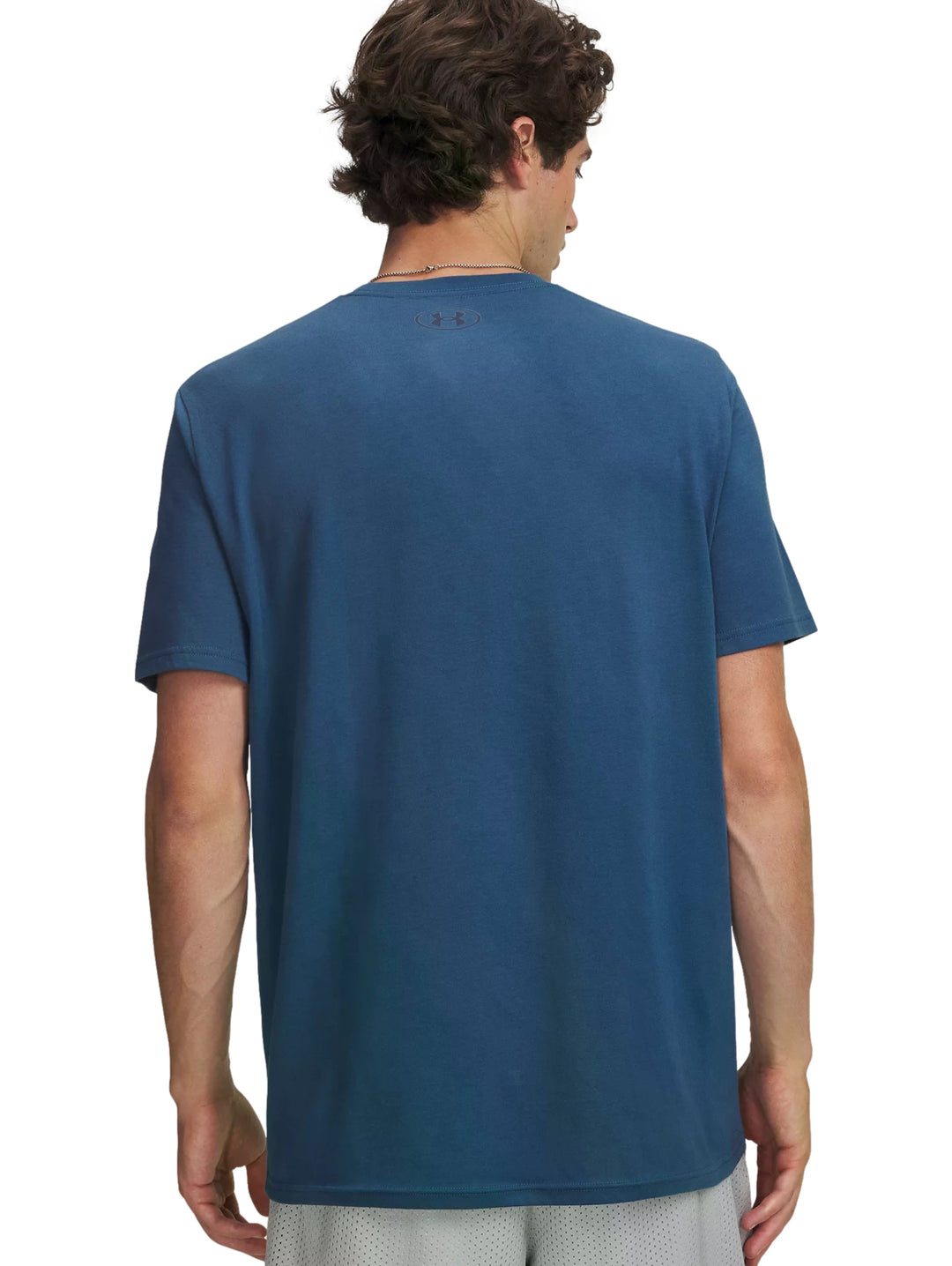 Hombre vistiendo una camiseta deportiva de color azul con logo de Under Armour en el pecho.