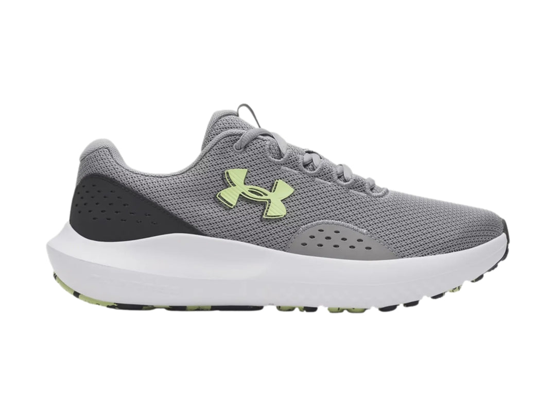 Tenis deportivos Under Armour Charged Surge 4 en color gris con suela blanca y logo en tono verde lima.