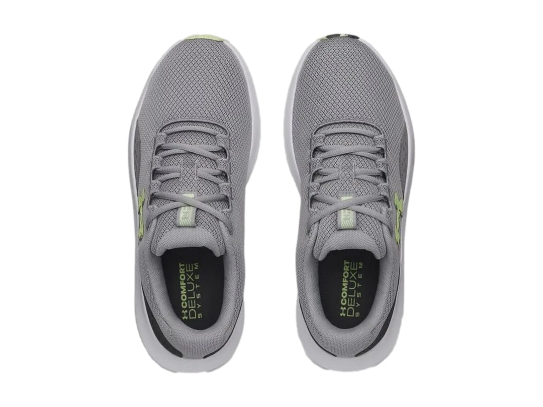 Tenis deportivos Under Armour Charged Surge 4 en color gris con suela blanca y logo en tono verde lima.