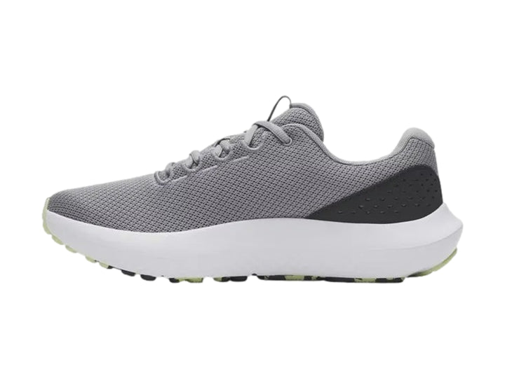 Tenis deportivos Under Armour Charged Surge 4 en color gris con suela blanca y logo en tono verde lima.