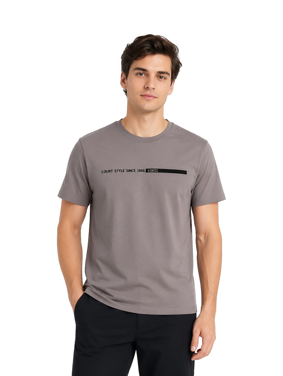 Hombre vistiendo playera K-Swiss color gris con detalle de texto negro en el pecho y pantalones negros.