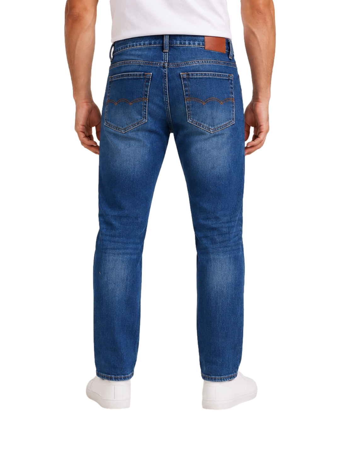 Hombre usando jeans de mezclilla azul medio con efecto roto y tenis blancos.