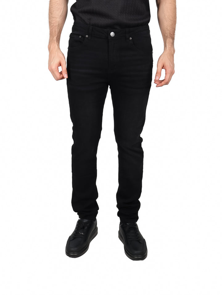 Hombre vistiendo pantalones jeans color negro de corte ajustado y zapatos negros.