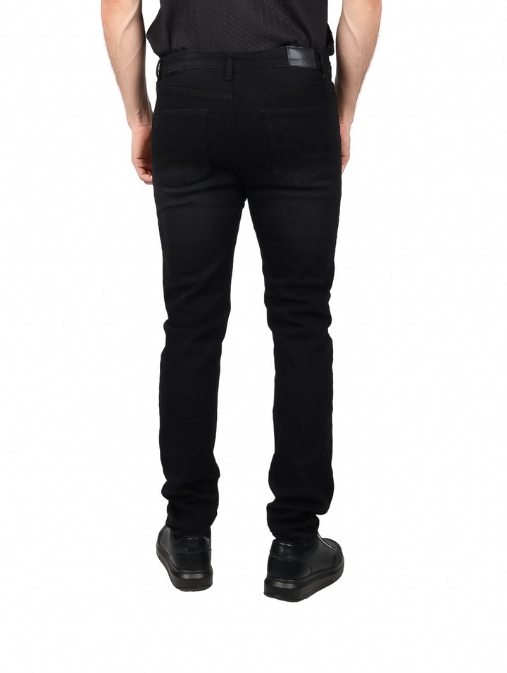 Hombre vistiendo pantalones jeans color negro de corte ajustado y zapatos negros.