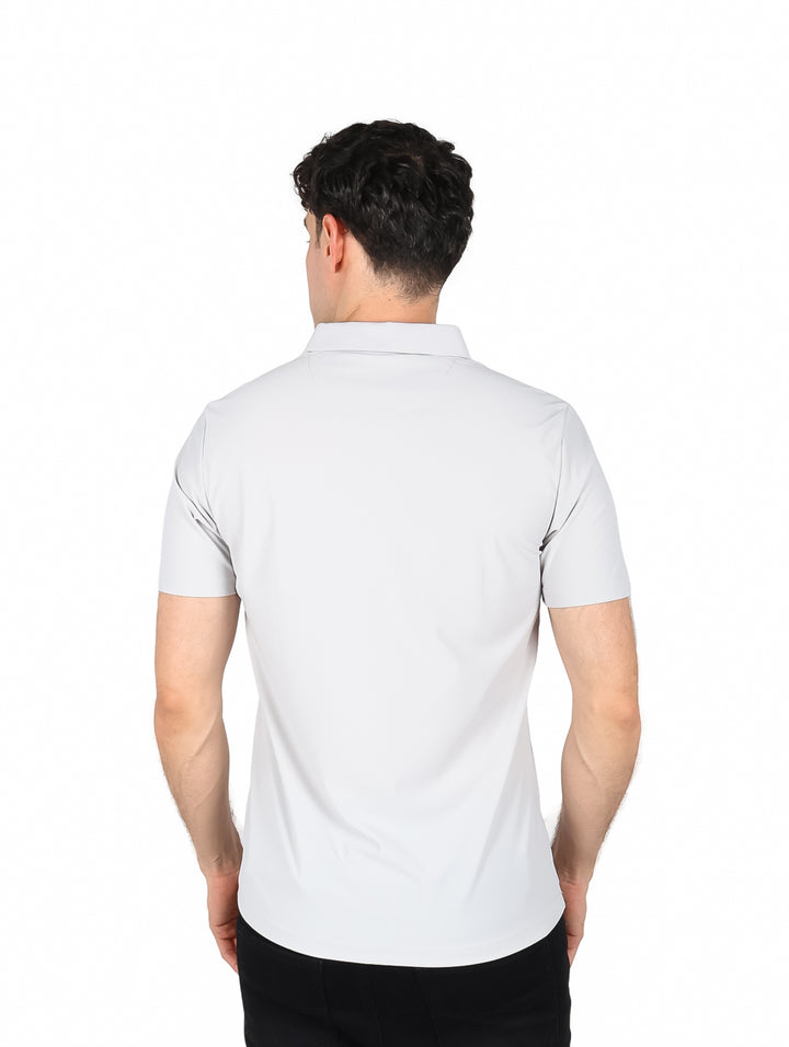 Hombre vistiendo playera polo color gris de manga corta y pantalones negros.