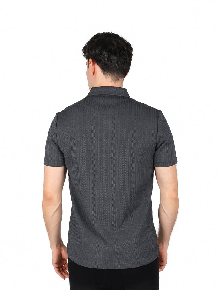 Hombre vistiendo playera polo color gris oscuro con textura vertical, cuello y manga corta.