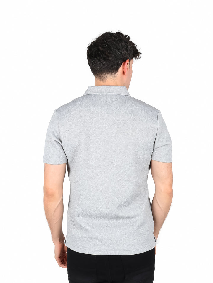 Hombre vistiendo playera polo color gris de manga corta con cuello y botones.