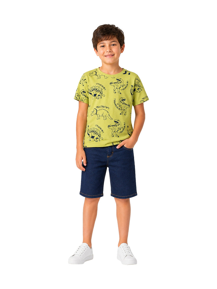 Niño vistiendo un conjunto de camiseta verde limón con estampados de dinosaurios y shorts de mezclilla azul.