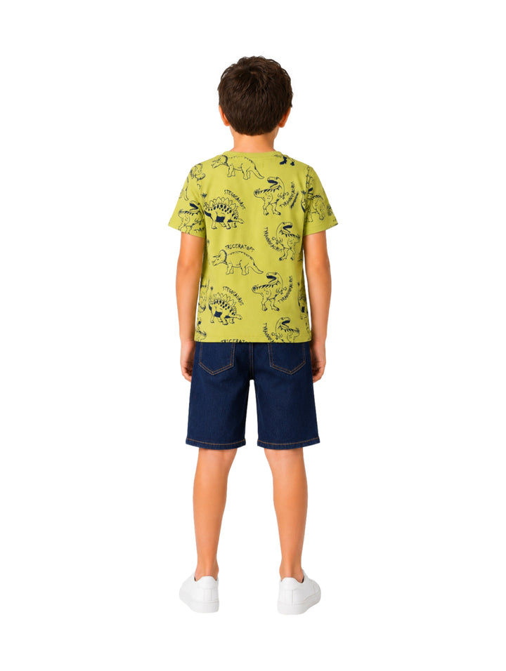 Niño vistiendo un conjunto de camiseta verde limón con estampados de dinosaurios y shorts de mezclilla azul.