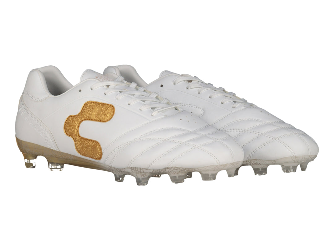 Zapato de fútbol Charly color blanco con detalles en dorado y suela de tacos transparente.
