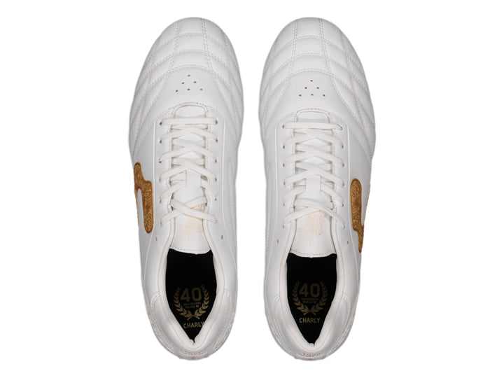 Zapato de fútbol Charly color blanco con detalles en dorado y suela de tacos transparente.