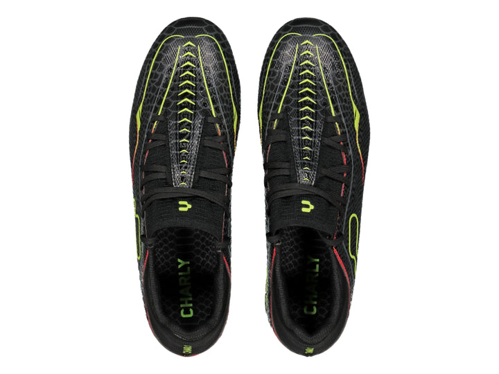 Zapato de fútbol Charly color negro con detalles en amarillo limón y rojo, vista lateral.
