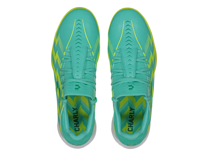 Zapato de fútbol turf Charly color turquesa con patrones zig-zag amarillos y suela amarilla.