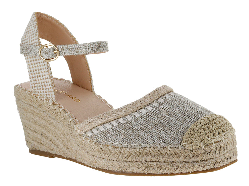 Sandalia de cuña color beige con punta cerrada, correa al tobillo y suela de fibras naturales tejidas.
