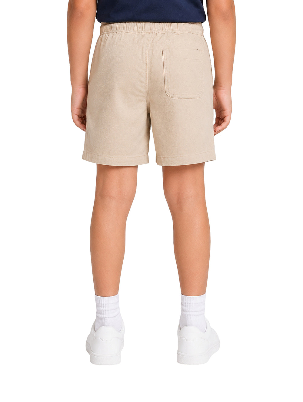 Niño vistiendo un short color beige con cintura elástica y tenis blancos.