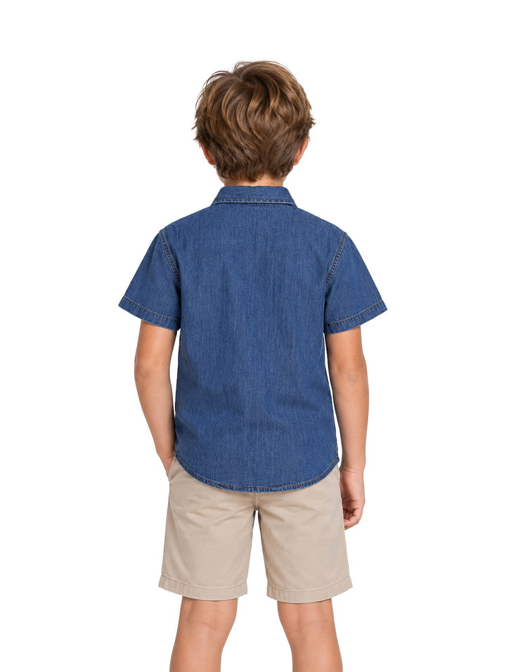 Niño vistiendo una camisa de mezclilla azul de manga corta con botones y un bolsillo en el pecho.