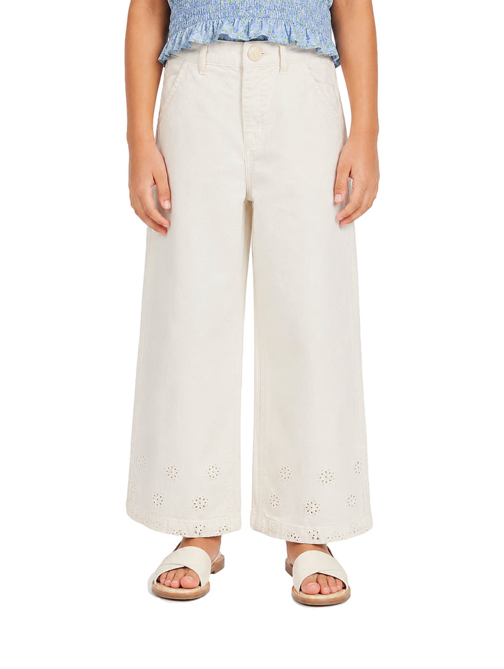 Pantalón beige claro para niña con pierna ancha y detalles bordados en la parte inferior.