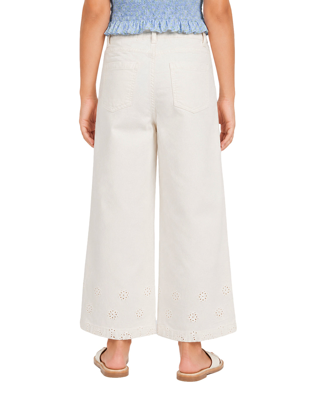 Pantalón beige claro para niña con pierna ancha y detalles bordados en la parte inferior.