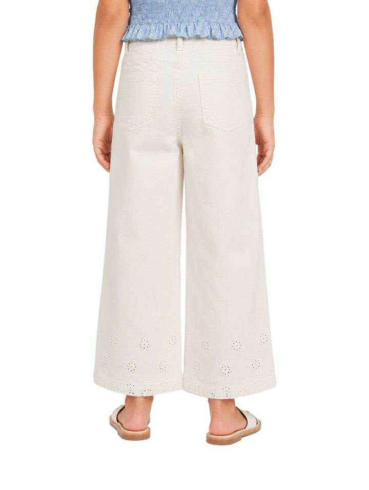 Pantalón beige claro para niña con pierna ancha y detalles bordados en la parte inferior.