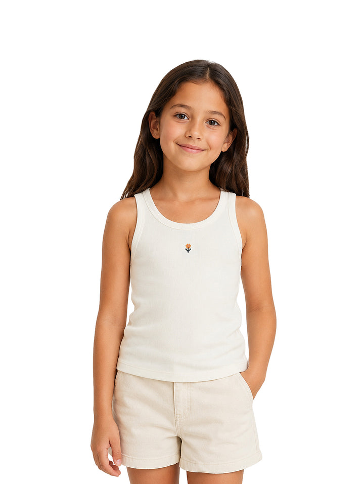 Niña vistiendo camiseta sin mangas y shorts en color beige claro con un pequeño detalle floral bordado.