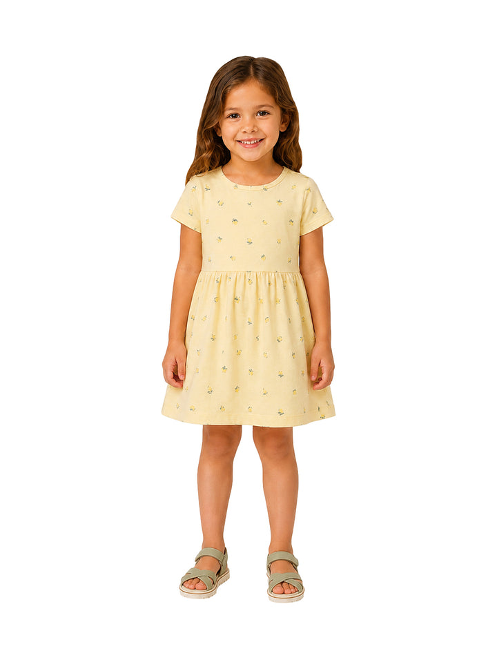 Niña con vestido corto color amarillo pálido con estampado floral pequeño.