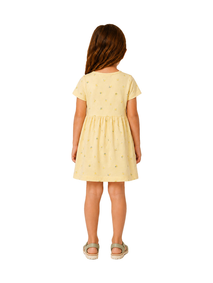 Niña con vestido corto color amarillo pálido con estampado floral pequeño.