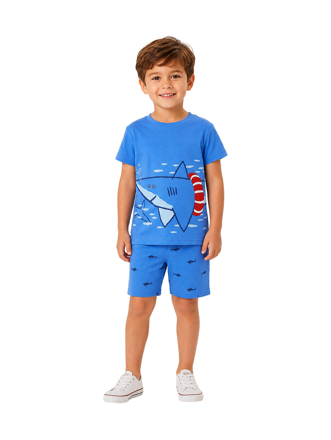 Niño vistiendo conjunto de camiseta y shorts azules con estampado de tiburón y tenis blancos.