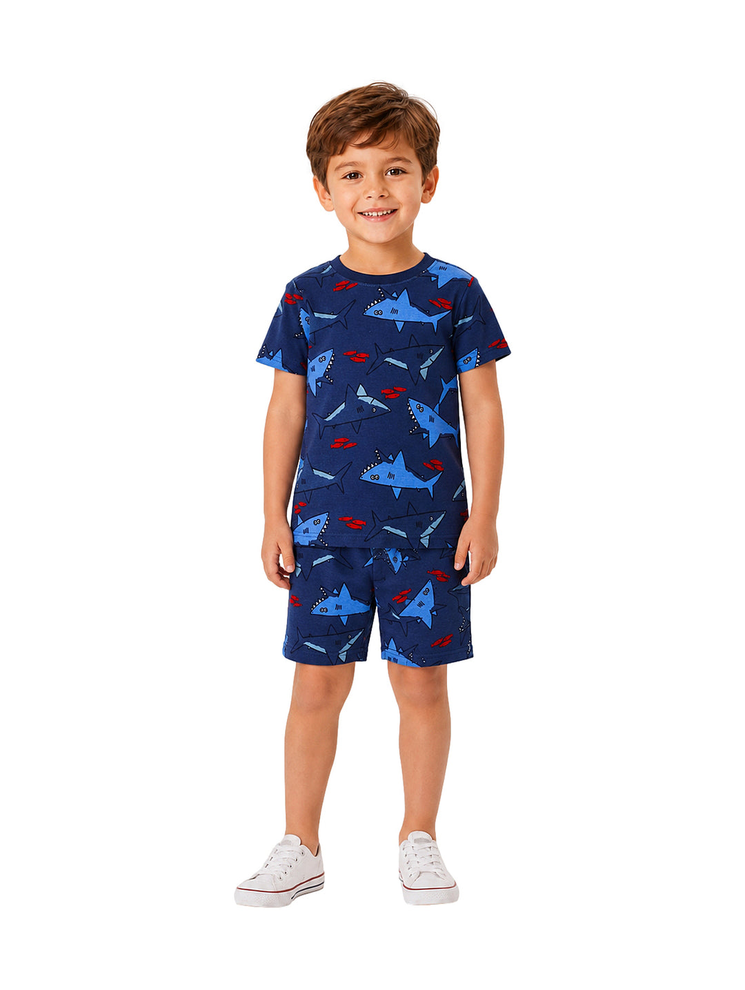 Niño vistiendo conjunto de camiseta y shorts azules con estampado de tiburón y tenis blancos.