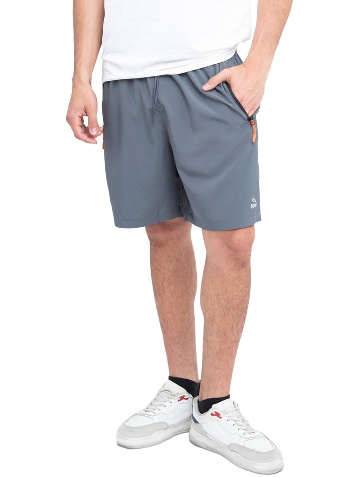 Hombre vistiendo shorts deportivos de color gris marca Voit con detalles en naranja en los bolsillos.