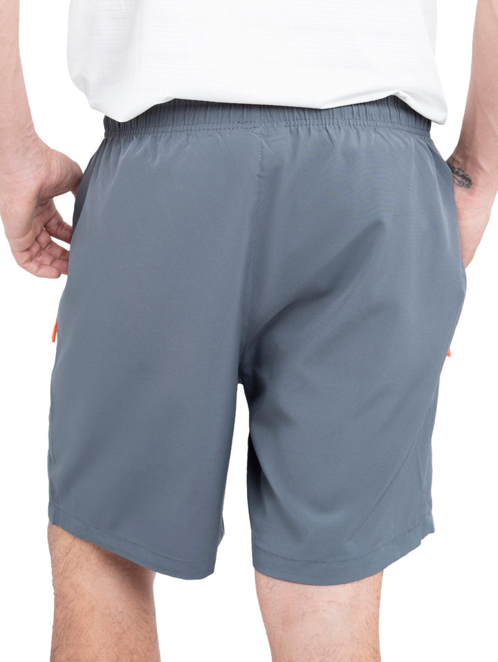 Hombre vistiendo shorts deportivos de color gris marca Voit con detalles en naranja en los bolsillos.
