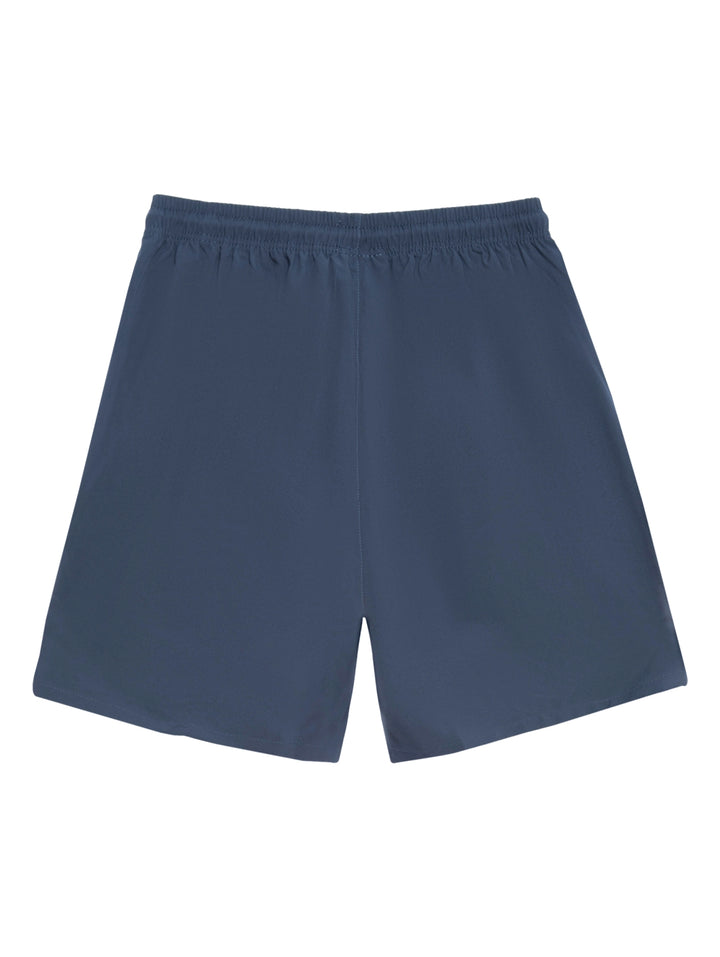 Hombre vistiendo shorts deportivos de color azul marino con detalles en naranja y calzado blanco.