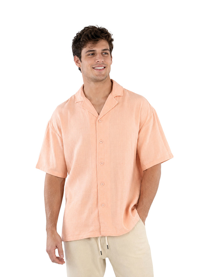 Hombre vistiendo una camisa de manga corta color coral claro con botones frontales.