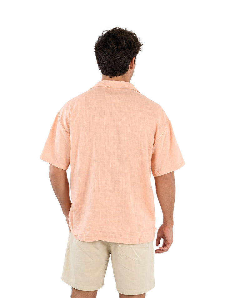 Hombre vistiendo una camisa de manga corta color coral claro con botones frontales.