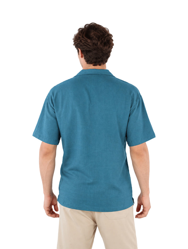 Hombre vistiendo una camisa azul de manga corta con botones y cuello, estilo casual.
