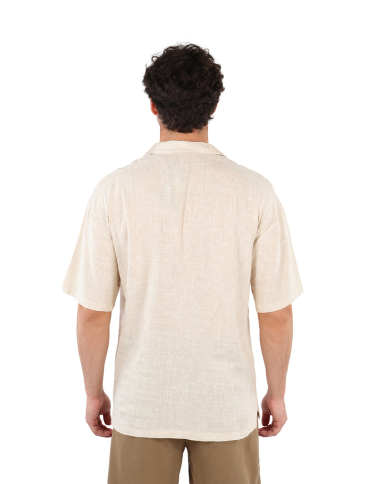 Hombre vistiendo una camisa de manga corta color beige con botones y pantalones caqui.