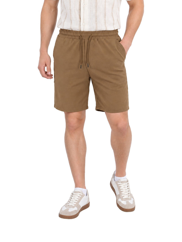 Hombre vistiendo un short corto de color café con cintura elástica y jareta, estilo casual.