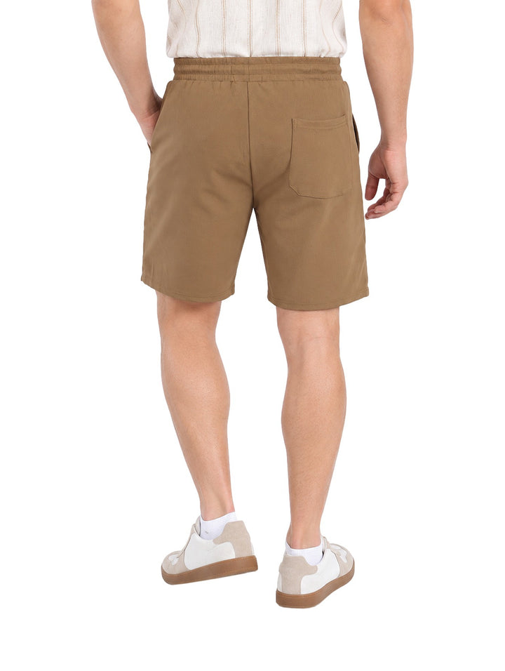 Hombre vistiendo un short corto de color café con cintura elástica y jareta, estilo casual.